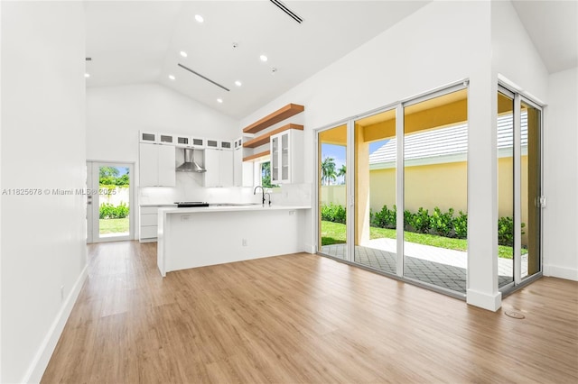 9047 Baybury Ln, West Palm Beach, FL 33411 - kitchen with wall chimney exhaust hood, recessed lighting, glass insert cabinets, white cabinetry, and a peninsula