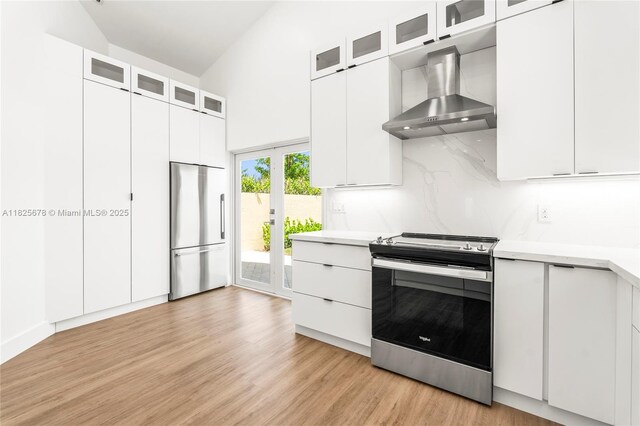 9047 Baybury Ln, West Palm Beach, FL 33411 - kitchen featuring appliances with stainless steel finishes, wall chimney range hood, light countertops, light wood finished floors, and high vaulted ceiling