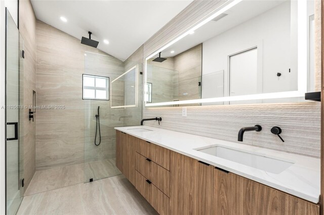 9047 Baybury Ln, West Palm Beach, FL 33411 - full bathroom with a stall shower, lofted ceiling, double vanity, tile walls, and tasteful backsplash