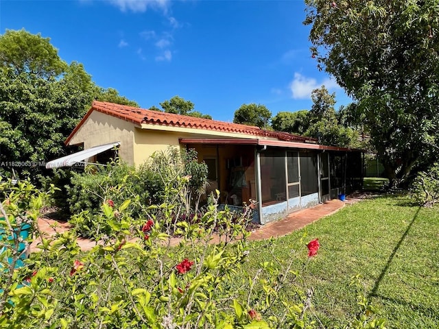 3880 NW 2nd Ter, Miami, FL 33126 - rear view of house featuring a sunroom, a yard, a tiled roof, and stucco siding