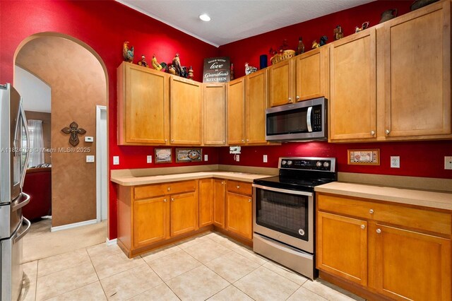 1025 SW Placetas Ave, Port St Lucie, FL 34953 - kitchen featuring appliances with stainless steel finishes, light countertops, brown cabinetry, light tile patterned flooring, and recessed lighting