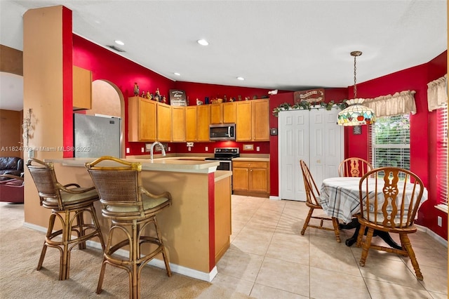 1025 SW Placetas Ave, Port St Lucie, FL 34953 - kitchen featuring stainless steel appliances, a peninsula, lofted ceiling, light countertops, and brown cabinetry