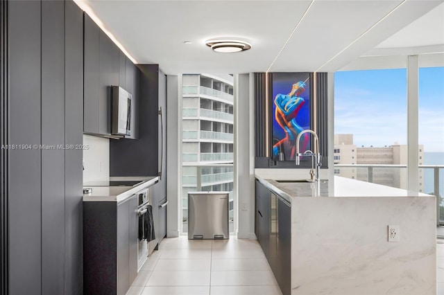 401 N Birch Rd Unit 1100, Fort Lauderdale, FL 33304 - kitchen with modern cabinets, stainless steel microwave, light countertops, light tile patterned flooring, and dark cabinetry