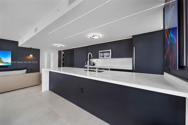 401 N Birch Rd Unit 1100, Fort Lauderdale, FL 33304 - kitchen featuring stainless steel microwave, light countertops, dark cabinets, modern cabinets, and light tile patterned flooring
