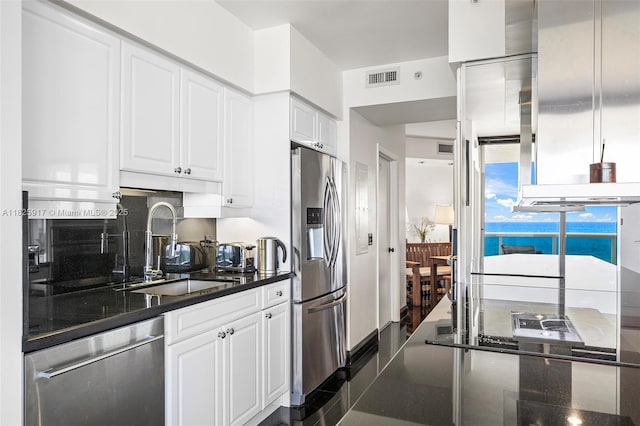 4779 Collins Ave Unit 702, Miami Beach, FL 33140 - kitchen with appliances with stainless steel finishes, white cabinets, and dark stone countertops