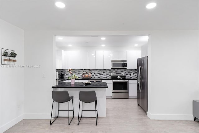 5290 Palm Ave, Hialeah, FL 33012 - kitchen featuring stainless steel appliances, a peninsula, a kitchen breakfast bar, white cabinets, and dark countertops