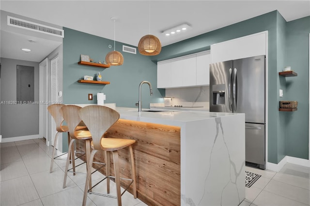 1111 SW 1st Ave Unit 721-N, Miami, FL 33130 - kitchen with stainless steel refrigerator with ice dispenser, white cabinetry, light tile patterned floors, decorative light fixtures, and light countertops