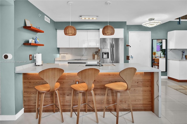 1111 SW 1st Ave Unit 721-N, Miami, FL 33130 - kitchen featuring stainless steel fridge with ice dispenser, white cabinetry, pendant lighting, a breakfast bar, and backsplash