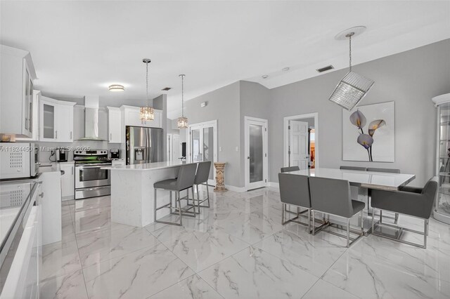 8905 NW 112th St, Hialeah Gardens, FL 33018 - kitchen with appliances with stainless steel finishes, wall chimney exhaust hood, a kitchen island, a kitchen bar, and white cabinets