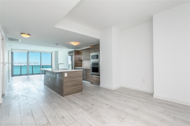 460 NE 28th St Unit 1905, Miami, FL 33137 - kitchen with modern cabinets, appliances with stainless steel finishes, light countertops, light wood-style flooring, and a center island with sink
