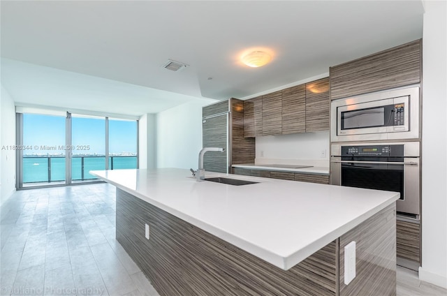 460 NE 28th St Unit 1905, Miami, FL 33137 - kitchen featuring appliances with stainless steel finishes, modern cabinets, light countertops, brown cabinets, and a wall of windows