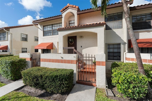 602 Lincoln Ct Unit 602, Deerfield Beach, FL 33442 - view of front of property featuring a gate, stucco siding, a fenced front yard, and a tiled roof
