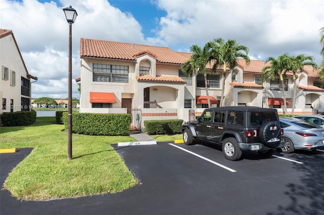 602 Lincoln Ct Unit 602, Deerfield Beach, FL 33442 - view of front of property with a tiled roof, stucco siding, uncovered parking, a front lawn, and a residential view