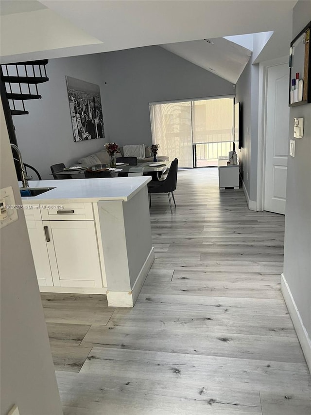 12922 SW 88th Ter Unit B-206, Miami, FL 33186 - kitchen featuring vaulted ceiling, light wood-style flooring, white cabinets, and light countertops