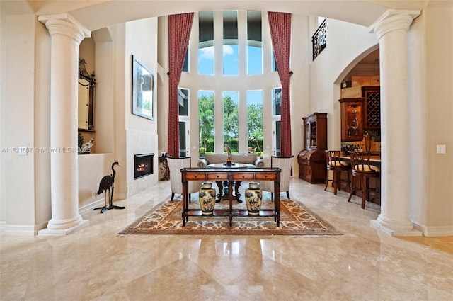 12608 S Stonebrook Cir, Davie, FL 33330 - dining area with ornate columns, arched walkways, marble tiled floors, a fireplace with flush hearth, and a high ceiling