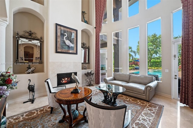 12608 S Stonebrook Cir, Davie, FL 33330 - living room featuring built in features, healthy amount of natural light, a tile fireplace, and a towering ceiling