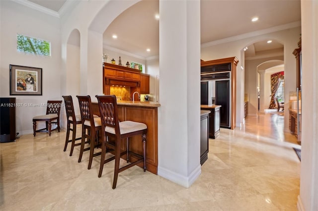12608 S Stonebrook Cir, Davie, FL 33330 - indoor wet bar featuring ornamental molding, recessed lighting, arched walkways, paneled refrigerator, and light marble finish floors