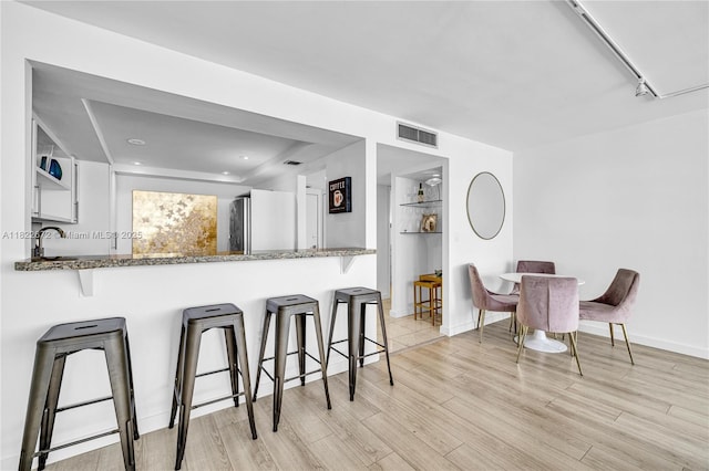 11 Island Ave Unit 1103, Miami Beach, FL 33139 - kitchen with light wood-style flooring, stone countertops, a kitchen breakfast bar, and refrigerator