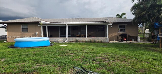 27064 Omni Ln, Punta Gorda, FL 33983 - back of house featuring a sunroom, stucco siding, a lawn, and a shingled roof