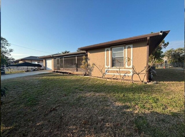 27064 Omni Ln, Punta Gorda, FL 33983 - view of side of home with a garage, driveway, a yard, and stucco siding