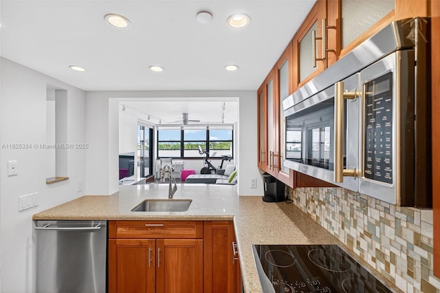 2555 Collins Ave Unit 606, Miami Beach, FL 33140 - kitchen with appliances with stainless steel finishes, glass insert cabinets, brown cabinets, tasteful backsplash, and light stone countertops