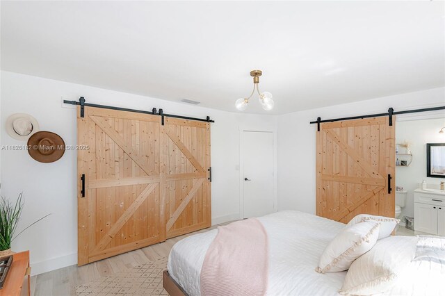 1770 NW 106th Ave, Pembroke Pines, FL 33026 - bedroom with a barn door, light wood-style flooring, and ensuite bathroom