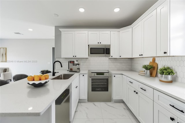626 Hobart Ave S, Lehigh Acres, FL 33974 - kitchen with range, a peninsula, dishwasher, light marble finish floors, and white cabinetry