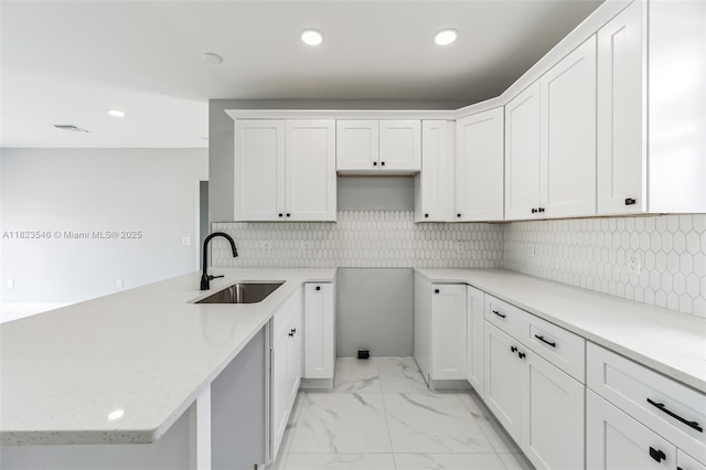 626 Hobart Ave S, Lehigh Acres, FL 33974 - kitchen with a peninsula, light marble finish floors, white cabinetry, recessed lighting, and backsplash