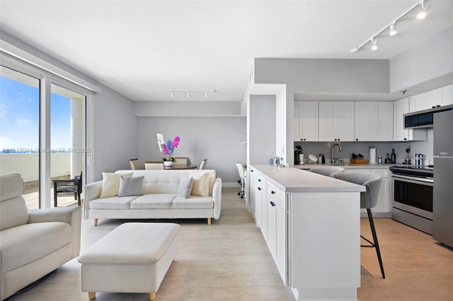 1621 Bay Rd Unit Ph3, Miami Beach, FL 33139 - kitchen featuring track lighting, electric range, a breakfast bar area, and open floor plan
