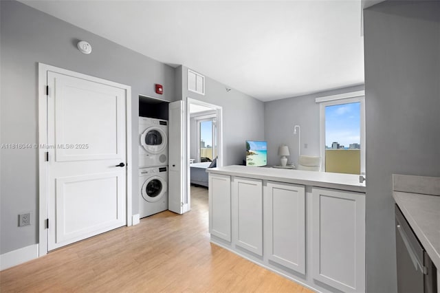 1621 Bay Rd Unit Ph3, Miami Beach, FL 33139 - laundry area featuring stacked washer and clothes dryer, light wood-style floors, and healthy amount of natural light