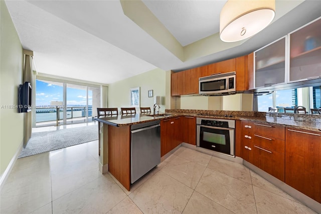 480 NE 30th St Unit 1402, Miami, FL 33137 - kitchen featuring appliances with stainless steel finishes, brown cabinets, a peninsula, dark stone countertops, and modern cabinets
