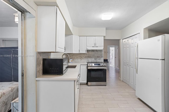 6441 NW 26th St, Sunrise, FL 33313 - kitchen with freestanding refrigerator, stainless steel range with electric stovetop, under cabinet range hood, light countertops, and white cabinets