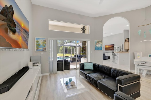 1137 SW Lighthouse Dr, Palm City, FL 34990 - living area featuring arched walkways, light wood-style floors, a towering ceiling, and recessed lighting