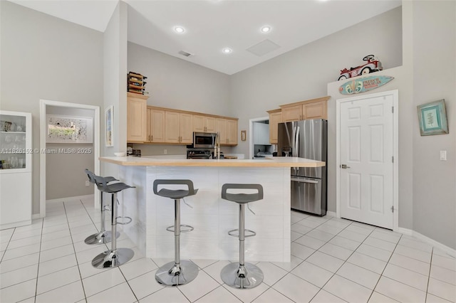 1137 SW Lighthouse Dr, Palm City, FL 34990 - kitchen featuring stainless steel appliances, light brown cabinets, a breakfast bar area, a peninsula, and light tile patterned floors