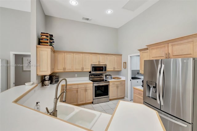 1137 SW Lighthouse Dr, Palm City, FL 34990 - kitchen featuring stainless steel appliances, light brown cabinets, washer and clothes dryer, light countertops, and a towering ceiling