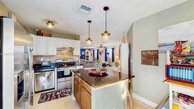 5637 SW 40th St, West Park, FL 33023 - kitchen with stainless steel appliances, under cabinet range hood, dark countertops, decorative backsplash, and white cabinetry