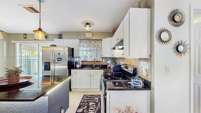 5637 SW 40th St, West Park, FL 33023 - kitchen featuring appliances with stainless steel finishes, dark countertops, under cabinet range hood, white cabinets, and tasteful backsplash