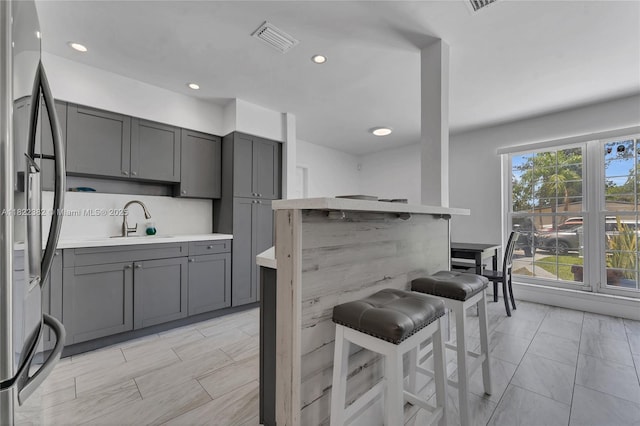 7540 Simms St, Hollywood, FL 33024 - kitchen with stainless steel refrigerator, gray cabinets, a breakfast bar area, light countertops, and recessed lighting