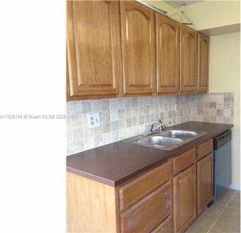 8917 NW 28th Dr Unit C-51, Coral Springs, FL 33065 - kitchen with stainless steel dishwasher, dark countertops, tasteful backsplash, and brown cabinetry