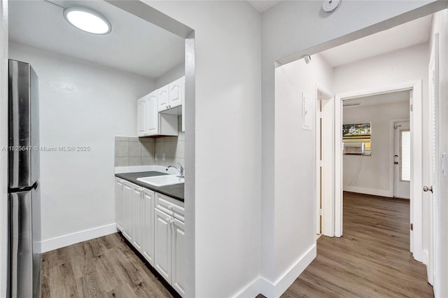 2106 NE 56th Ct Unit 108, Fort Lauderdale, FL 33308 - kitchen featuring freestanding refrigerator, white cabinets, light wood-style flooring, and tasteful backsplash