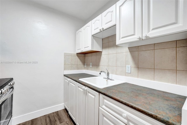 2106 NE 56th Ct Unit 108, Fort Lauderdale, FL 33308 - kitchen featuring decorative backsplash, white cabinetry, stainless steel range with electric cooktop, dark countertops, and dark wood-type flooring