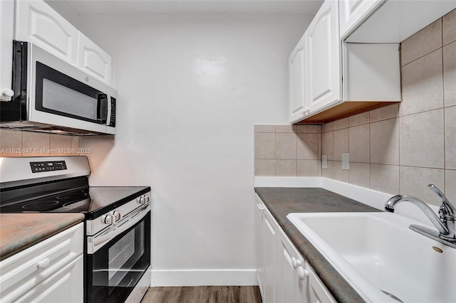 2106 NE 56th Ct Unit 108, Fort Lauderdale, FL 33308 - kitchen with appliances with stainless steel finishes, wood finished floors, white cabinetry, and decorative backsplash