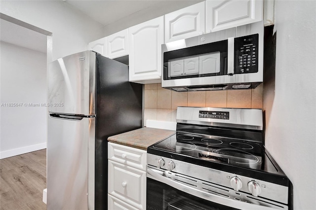 2106 NE 56th Ct Unit 108, Fort Lauderdale, FL 33308 - kitchen featuring appliances with stainless steel finishes, white cabinetry, tasteful backsplash, wood finished floors, and light countertops