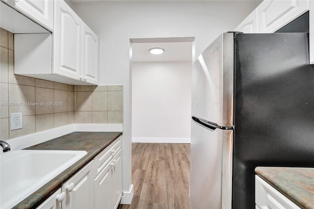 2106 NE 56th Ct Unit 108, Fort Lauderdale, FL 33308 - kitchen featuring freestanding refrigerator, white cabinets, tasteful backsplash, and light wood-style floors