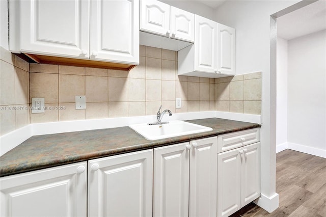 2106 NE 56th Ct Unit 108, Fort Lauderdale, FL 33308 - kitchen with dark countertops, white cabinets, wood finished floors, and backsplash