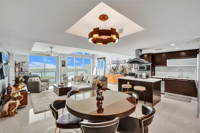 7930 E Dr Unit 1806, North Bay Village, FL 33141 - dining room with a raised ceiling, light tile patterned floors, a chandelier, and a wall of windows