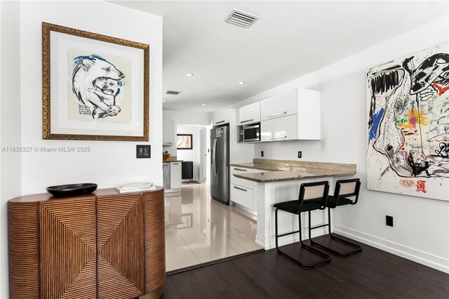 600 NE 55th Ter, Miami, FL 33137 - kitchen with appliances with stainless steel finishes, white cabinetry, a peninsula, recessed lighting, and a breakfast bar