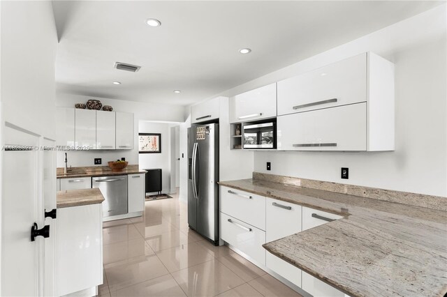 600 NE 55th Ter, Miami, FL 33137 - kitchen featuring stainless steel appliances, modern cabinets, white cabinetry, light tile patterned floors, and recessed lighting