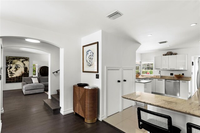 600 NE 55th Ter, Miami, FL 33137 - kitchen featuring dishwasher, white cabinetry, arched walkways, wood finished floors, and recessed lighting