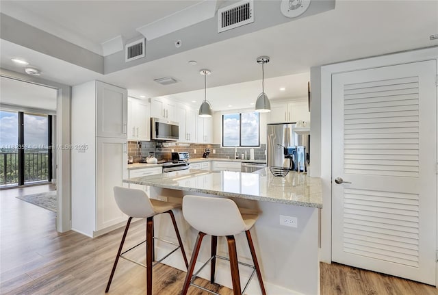 200 Ocean Trail Way Unit 701, Jupiter, FL 33477 - kitchen featuring appliances with stainless steel finishes, tasteful backsplash, white cabinets, light wood-type flooring, and a breakfast bar area